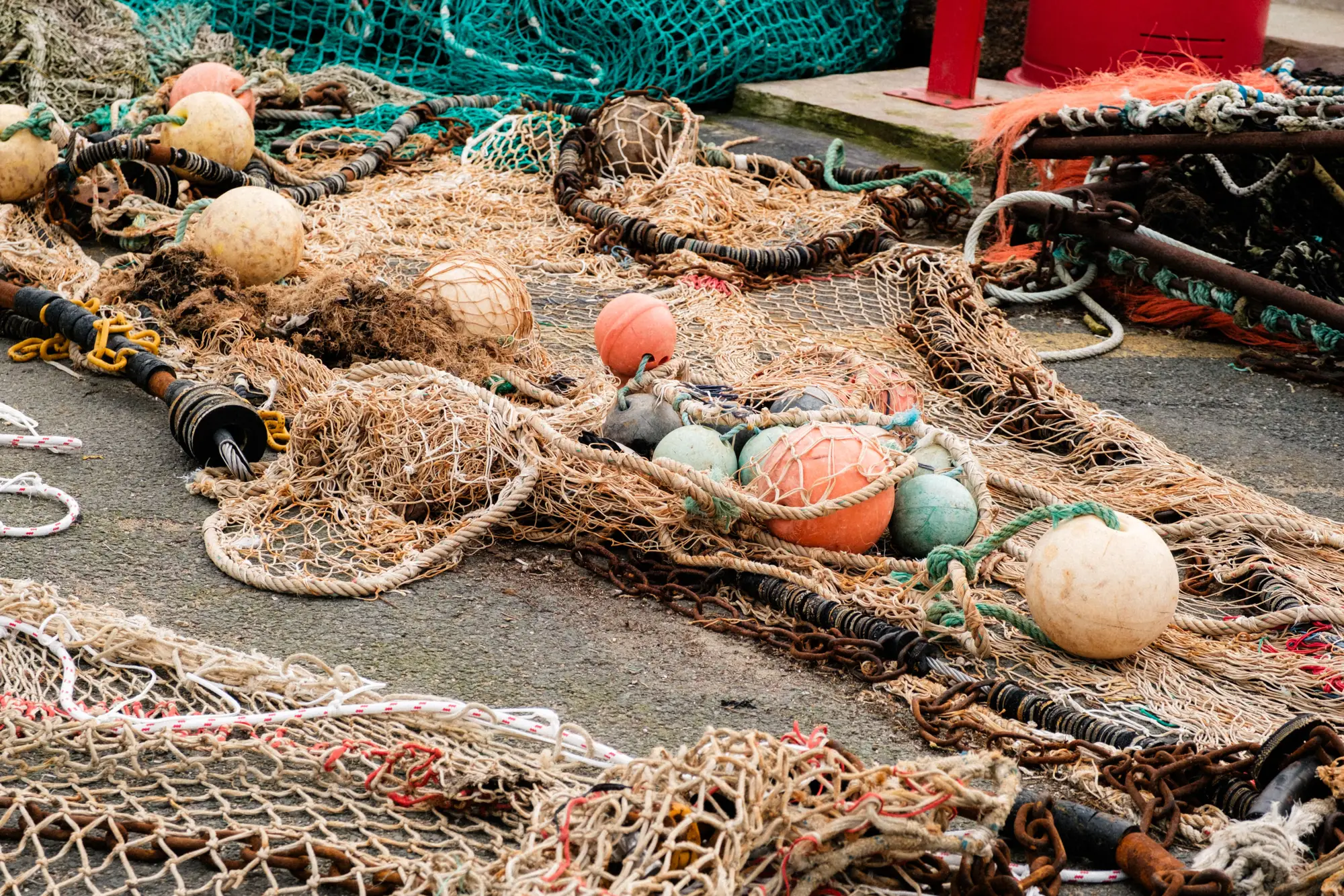 Fishing nets, floats and chain heaped on a quayside